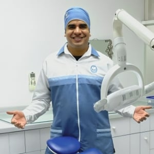 Dr. Alejandro Pena in a blue and white scrubs and blue surgical cap inside a dental clinic